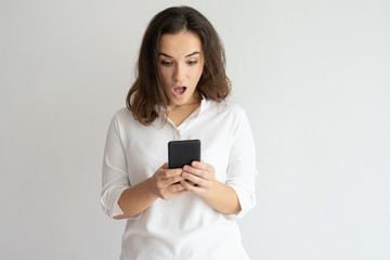 Shocked woman holding smartphone and looking at its screen