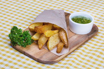 potatoes cooked in rustic, wrapped in an envelope served on a wooden board, along with pesto sauce.