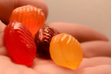 Hard sugar candies in hand.. Multi colored  with fruit flavor boiled sweeties or sugar plums in hand. Suitable for use as a cough drops. Close-up 