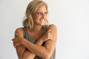 Fototapeta premium Positive tanned young lady holding shoulders and looking aside