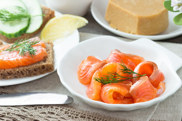 Traditional Norwegian breakfast, sandwiches with brown cheese brunost, sandwiches with cucumber and trout.