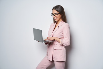 Confident business woman wearing pink suit holding opened laptop