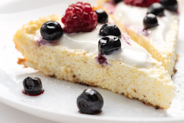 Cheesecake with cream and fresh raspberries and blueberries.