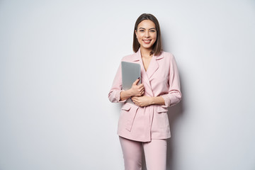 Confident business woman wearing pink suit with laptop underarm