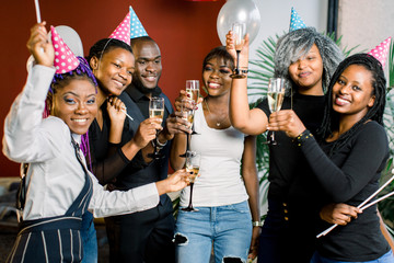 Group of happy africans friends drinking champagne and celebrating New Year. New year party....
