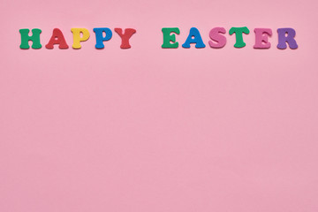 Pink Easter background. Colorful letters forming words HAPPY EASTER on pink background. Copy space for your text.
