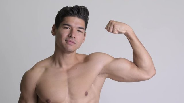 Young handsome muscular shirtless man showing biceps