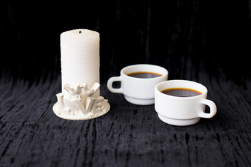 candle and two cups of coffee on a black background
