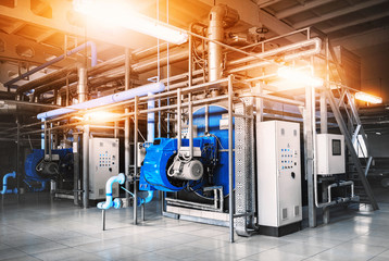 interior of the boiler room with two gas boilers, a control cabinet and pipes for supplying gas and steam. Three-quarter view. Blue tinting with lamps on