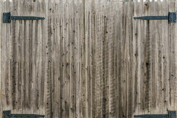 Centered view of an old weathered, aged,  wooden gate with iron door hinges, vertical lines, texture. Background, copy space