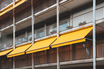 Nice balcony with yellow awning in apartment house. - obrazy, fototapety, plakaty