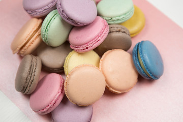 Cake macaroons or macaroons are laid out in a chaotic order on a pink background, colorful almond cookies, pastel colors