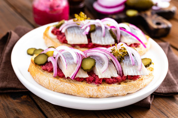 Delicious grilled sandwiches with herring, onion and beetroot sauce with horseradish on dark wooden rustic background. Danish cuisine