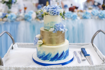 beautiful high wedding cake. white and blue festive cake decorated with a flowers on the table. sweet table on a wedding banquet in the restaurant.
