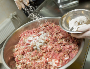 Stuffing with beef in the dishes with stainless steel, the cook prepares forcemeat for the cocktail, salt minced meat.
