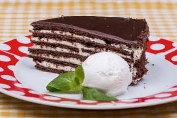 A slice of rich moist chocolate cake on a white plate with layers. View from above. decorated with ice cream and mint. Restaurant
