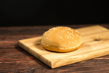A sesame seed bun on a wooden board