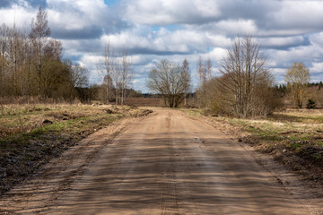 empty country gravel road with mud puddles and bumps