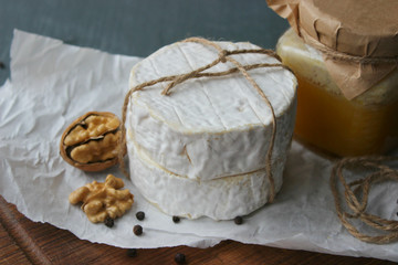 Camembert cheese close-up. Round Camembert cheese on the white paper, the background of the tree. Exquisite cheese, cheese plate, wine food. Camembert cheese. Fresh brie cheese and sliced on a wooden 