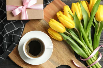 Beautiful tulips with notebooks and cup of coffee on light background, top view