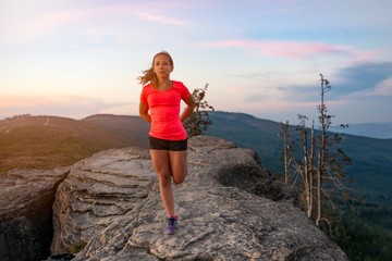 Woman cross country runner quads stretching in mountains at summer