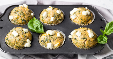 Muffins with spinach and feta cheese in a muffin tin. Light background. Copy space.