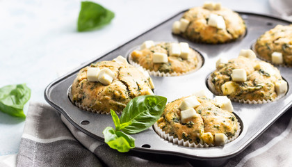 Muffins with spinach and feta cheese in a muffin tin. Light background. Copy space.