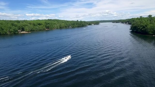 A white motor boat travels along a calm lake.