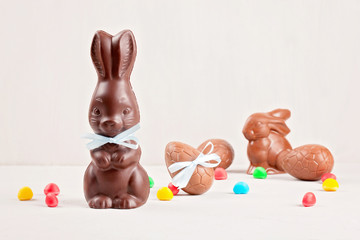 Easter composition with chocolate eggs and bunny on  wooden background, space for text