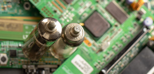 Old vacuum electronic radio tube against the background of the green board, close-up.