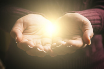 Abstract light in female hands, offering help, protection and support symbol. Sharing hope concept