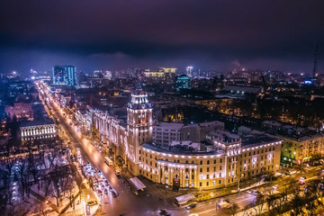Fototapeta na wymiar Arial view of Voronezh Main South-Eastern Railway Building tower in night, symbol of Voronezh and evening cityscape with rads, parks and traffic, drone shot