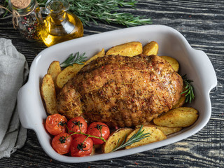 Roasted pork roulade, roll with potato and tomato in baking tray