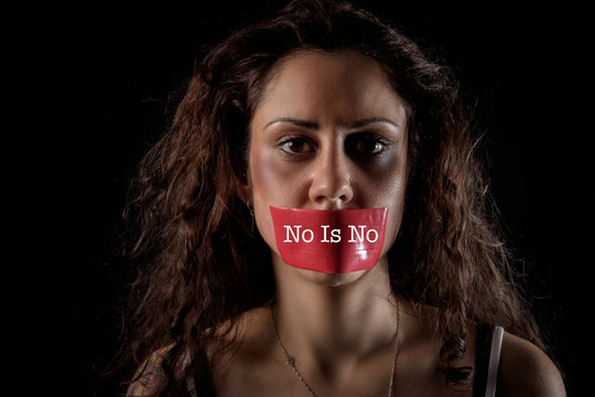 closeup portrait of a young woman with bruises and wounds marks on her face and her mouth is silenced with a red tape