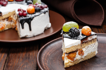 Delicious cake with fruit and berries decoration on wooden table