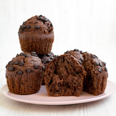 Chocolate cupcakes on pink plate on white wooden table, side view. Close-up.