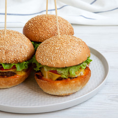 Cheeseburgers on grey plate on white wooden surface, low angle view. Closeup.