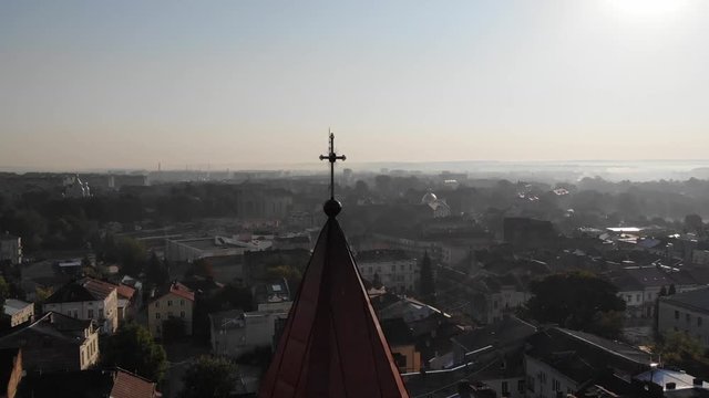 Aerial view of Landscape of Drohobych city. Smooth pan around dome of medieval Bell Tower of St.Bartholomew church with view of Drohobych City Hall and cityscape. Morning time, sunlight
