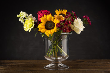 Bouquet of white yellow and red flowers in a vase on a dark background