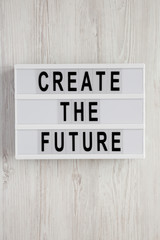 'Create the future' word on modern board on a white wooden background, top view. From above, flat lay, overhead.