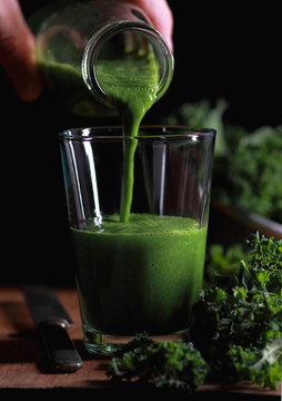 Glass with kale smoothie. Pouring smoothie for the bottle.