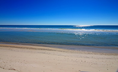 Gulf Shores beach in Alabama, the sunlight is reflecting off of the surf