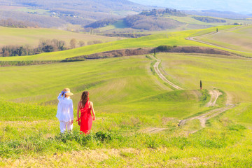 Fototapeta na wymiar Ragazze camminano in una strada tra le verdi colline