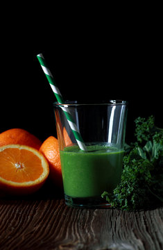Glass with green smoothie on black background