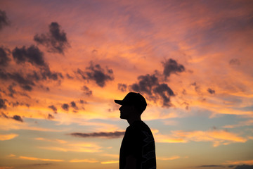 Side view of man standing against cloudy sky during sunset