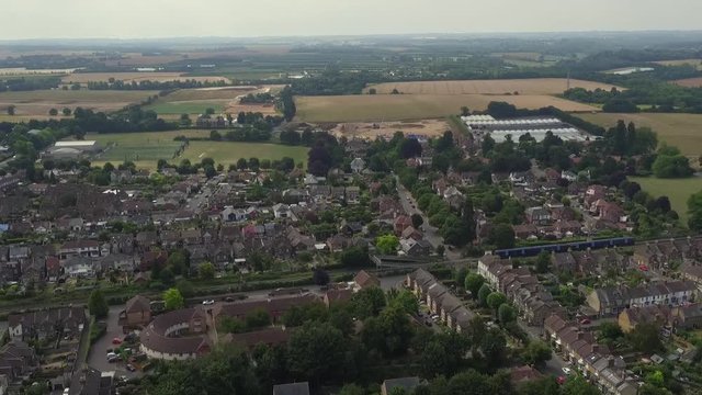 Tracking aerial shot of a commuter train passing through the town of Faversham, Kent, UK