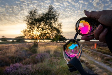 Holding festival kaleidoscope goggles at sunset