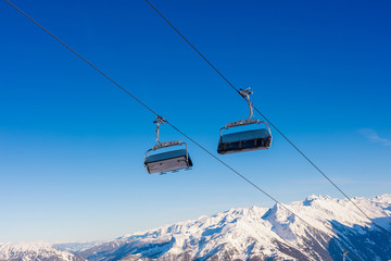 Fototapeta na wymiar Ski lift with seats going over the mountain