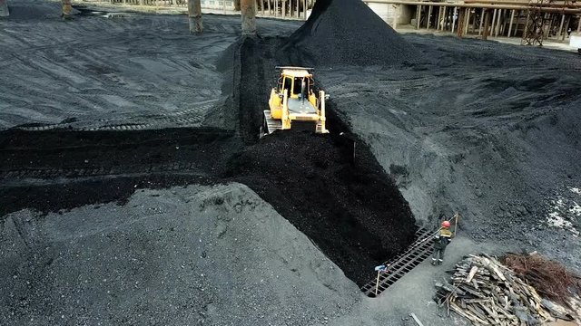 Moving tractor coal around plant for processing. Coal Production. Aerial view.