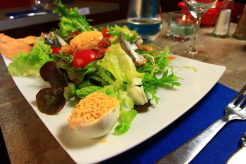 Salad prepared with mimosas eggs and a portion of onion pie in a French restaurant